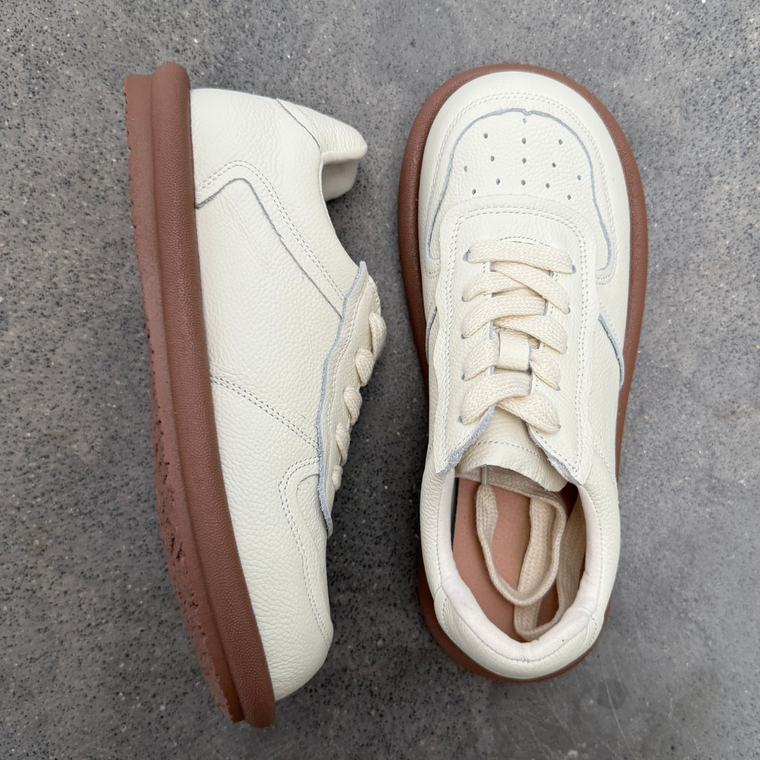 White sneakers with brown soles on a gray surface