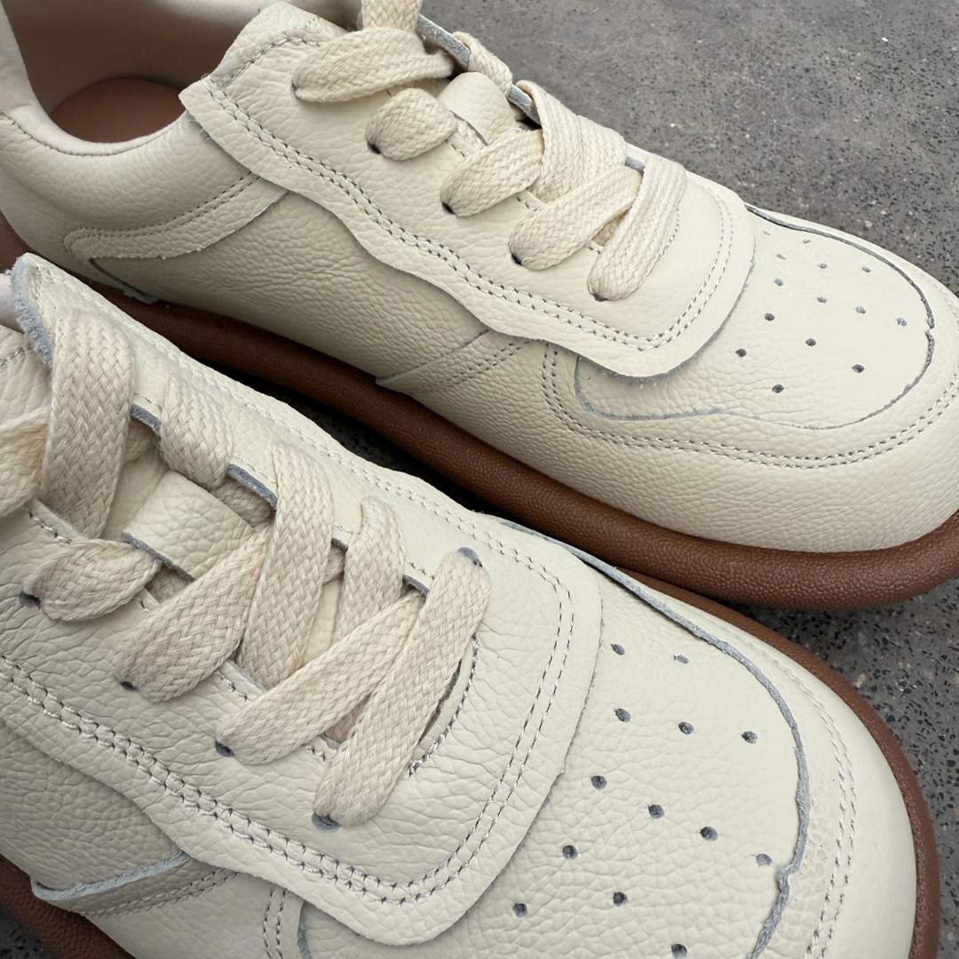 Close-up of beige sneakers with brown soles on a concrete surface